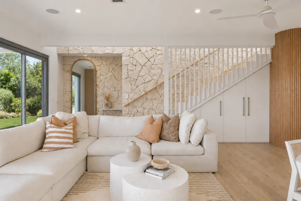 Salon à la décoration intemporelle et minimaliste, couleur douce, mobilier cosy, matières naturelles, escalier et miroir